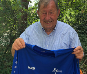 « Il présente le nouveau maillot de l’équipe corpo du Conseil départemental de l’Yonne : Guy ROUX reprend du service en devenant entraîneur d’honneur ! ».