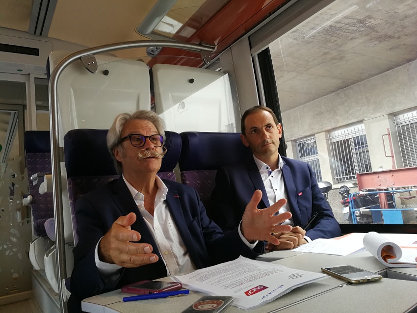  « C’est depuis une rame de TER en gare de Dijon que le premier vice-président de la Région Bourgogne Franche-Comté, Michel NEUGNOT (à gauche), et le directeur régional adjoint de SNCF Mobilités, Emmanuel GUIGON ont expliqué la stratégie de reconquête du réseau ferroviaire après les péripéties sociales du printemps. Une sensibilisation ouverte également aux personnes précaires et aux demandeurs d’emploi… ».