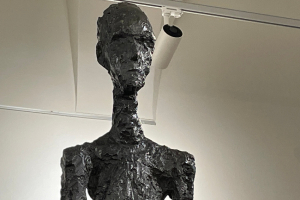 « C’est l’une des pièces maitresses de l’œuvre du peintre et sculpteur suisse Alberto GIACOMETTI. La « Femme debout », version II, représente plus qu’une icône de l’art moderne : elle est le symbole de la résistance et du déterminisme contre toutes les persécutions faites à l’homme par l’homme… ».
